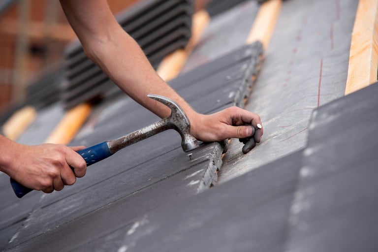 Close-up of skilled builder hands carefully placing roofing tiles on sloped surface